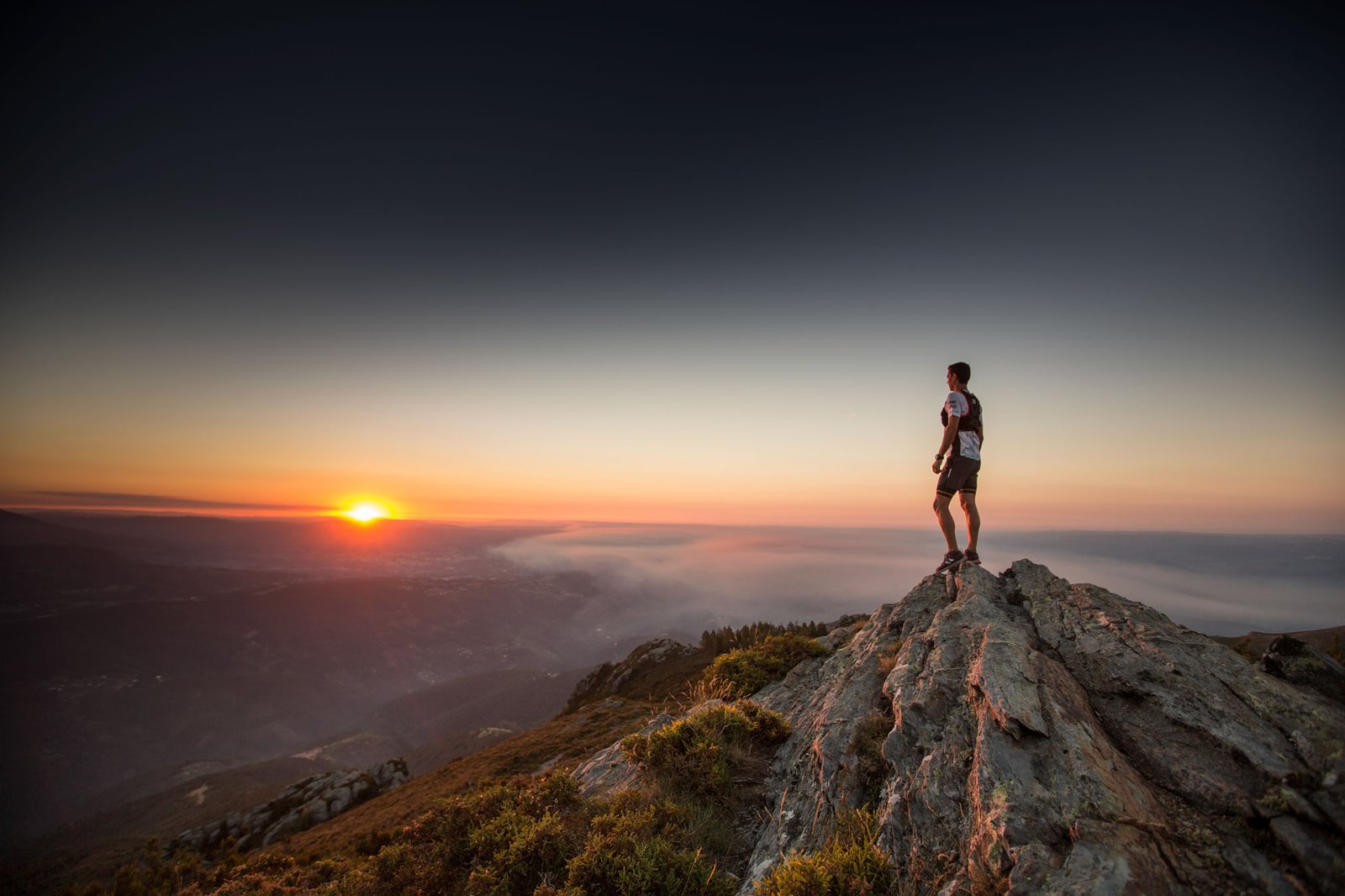 Atleta no cume de uma montanha ao pôr do sol, por Susana Luzir.