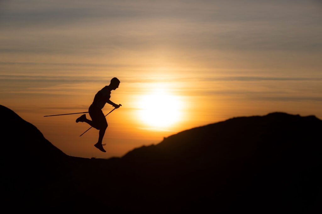 Silhueta de um atleta de trail ao pôr do sol, fotografada por Susana Luzir.
